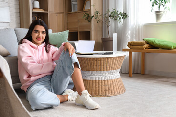 Wall Mural - Beautiful young woman in stylish hoodie sitting on floor at home