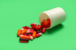 canvas print picture - Overturned bottle with different pills on green background