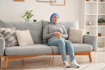 Canvas Print - Mature woman after chemotherapy sitting on sofa at home. Stomach cancer concept