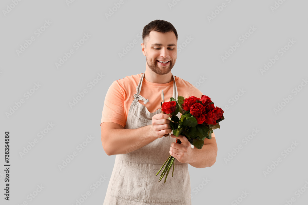 Male florist with flowers on light background