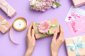 Sticker - Female hands with gift boxes and cards on purple background. International Women's Day