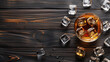 © Serhii - A glass of whiskey sits on a dark wooden table next to ice cubes, top view