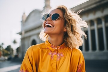 Wall Mural - Portrait of young beautiful woman in sunglasses smiling on the street.