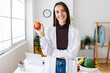 © Xavier Lorenzo - Smiling portrait of young nutritionist woman holding red organic apple at medical office. Healthy lifestyle and nutrition concept.