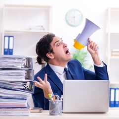 Wall Mural - Young male employee unhappy with excessive work