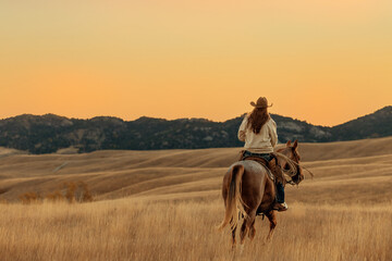 horse and cowgirl rider sunrise riding away