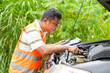 Car mechanic performs basic engine check and carrying a clipboard and a cost estimate for repairs from an engine breakdown