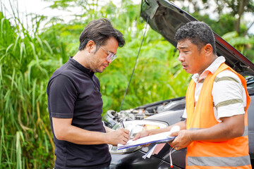 Wall Mural - A garage employee inspects a car with a broken engine. and have the owner sign an acknowledgment of the damage and agree to allow the technician to inspect and repair