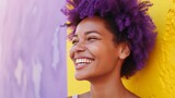Fototapeta Tęcza - A woman with a radiant smile and colorful hair stands joyously against a vivid yellow and purple background.