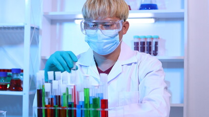 Scientists are doing research in a science lab. A medical chemist in a white coat, gloves and goggles looks at a glass tube. Compare two different liquid samples. and discuss future experiments.