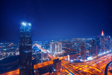 Wall Mural - Amazing skyline of city center Dubai. Aerial top view night cityscape with skyscrapers with illuminated and highway. Business and financial modern district of UAE.