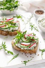 Wall Mural - Sandwiches with rye bread toasts, cottage cheese, radish, cucumber, fresh greens and arugula for a healthy breakfast