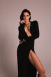 fashion photo of beautiful woman with dark hair in luxurious sexy black dress posing in the studio