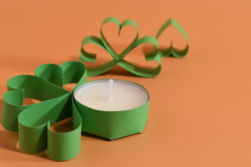 Four-leaf clover and candles on peatch background. St. Patrick's Day