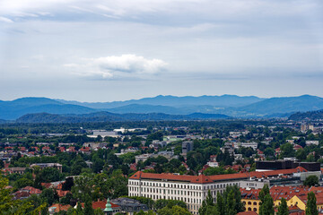 Wall Mural - Aerial view of City of Ljubljana seen from Sance castle hill with mountain panorama in the background on a cloudy summer day. Photo taken August 9th, 2023, Ljubljana, Slovenia.