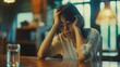 Sad, grief-stricken woman sitting alone at the kitchen table, depression and stress