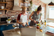 © Davor - Lesbian couple cooking with a laptop in the kitchen