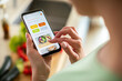 © Vorda Berge - Young woman using recipe app on smartphone for preparing meal at home