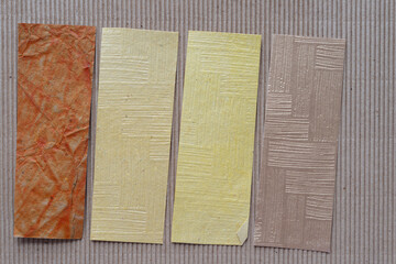 Sticker - four paper stripes with embossed textures on corrugated cardboard sheet