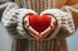 small red knitted heart on a hands of a person wearing knitted jumper sweater. 