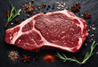Fresh raw marbled beef rib eye steak rosemary and spices on black stone background top view
