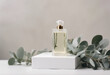 Glass perfume bottle on white podium Floral eucalyptus arrangement Minimal mockup style soft focus Organic essential oil and fresh eucalyptus twigs on pastel background with copy space for your design