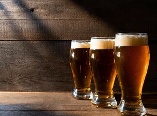 Wall Mural - Glasses of beer isolated on wooden background with copy space for design