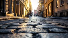 A Quaint Cobblestone Street Lined With Charming Buildings Against A Clear Blue Sky, Creating A Picturesque Outdoor Way To Travel Through The Bustling City Infrastructure