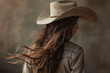 Close-up portrait of a young woman with long brown hair wearing a cowboy hat and western shirt - isolated, neutral studio background