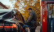 Mężczyzna na stacji benzynowej ładuje samochód elektryczny za pomocą szybkiej ładowarki