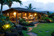 A Hawaiian bungalow, lanai, and yard  illuminated at dusk, with tropical landscaping.