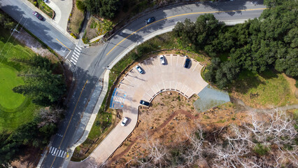 Aerial top down view of a circular parking lot next to t-intersection on curvy roads