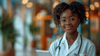 © Fokke Baarssen - Happy Black Woman Doctor smiling in the clinic office and looking into camera, woman with glasses