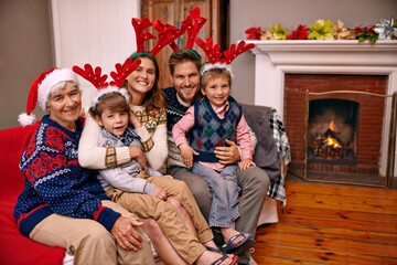 Poster - Christmas, portrait and happy big family on sofa in home for holiday or festive celebration. Xmas, parents and smile of children with grandmother in living room, antlers or bonding together at party