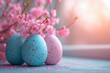 Pink and blue colored Easter eggs with blossoming pink twigs on a windowsill for Easter celebration with copy space. Shallow depth of field with glowing morning light