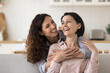 © fizkes - Happy Mothers Day celebration, family ties and unconditional love. Cheerful beautiful grown up millennial daughter cuddling from behind her lovely mature mother, express care, support and affection
