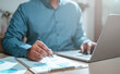 © sornthanashatr - business, finance, investment, financial, document, report, budget, account, accounting, analysis. businessman one hand typing keyboard and another use pen to calculation report and confirm to invest.
