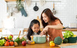 © Art_Photo - Portrait of enjoy happy love asian family mother with little asian girl daughter child help cooking food healthy eat with fresh vegetable testing smell soup in a pot with spoon.helping mommy