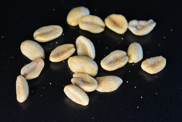 Wall Mural - Healthy foods, health, nuts, salted toasted peanuts are scattered chaotically on a black background.