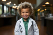 Young child wearing a doctor's white coat smiles sweetly at the camera.