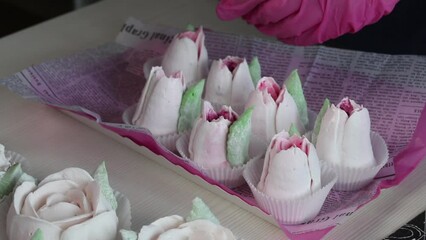 Wall Mural - A freelancer makes marshmallows at home. A woman puts zephyr in a package. Zephyr roses and tulips are laid out on the table. Close-up.