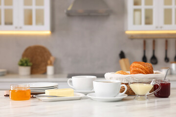 Wall Mural - Breakfast served in kitchen. Fresh croissants, coffee, butter, jam, honey and sweetened condensed milk on white table