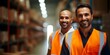 Male workers in orange vests smiling and posing in warehouse showcase teamwork. Concept Teamwork, Warehouse Setting, Male Workers, Orange Vests, Smiling and Posing
