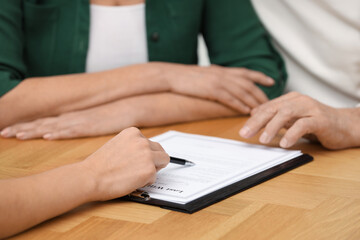 Canvas Print - Notary showing senior couple where to sign Last Will and Testament at wooden table, closeup