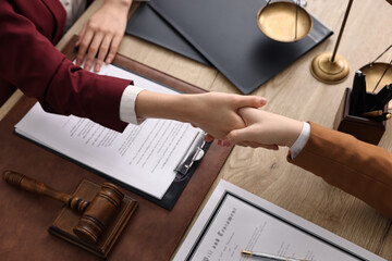 Wall Mural - Notary shaking hands with client at wooden table, closeup