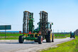 © Anton Vakhrushev - two agricultural tractors are driving along a rural asphalt road next to a field. selective focus