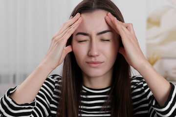 Canvas Print - Sad woman suffering from headache at home