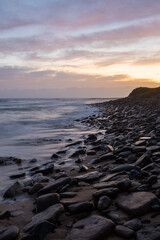 Wall Mural - Cloudy morning on the rocky beach shore.