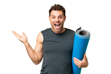 Wall Mural - Young sport man going to yoga classes while holding a mat over isolated chroma key background with shocked facial expression