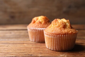 Delicious sweet muffins on wooden table, closeup. Space for text